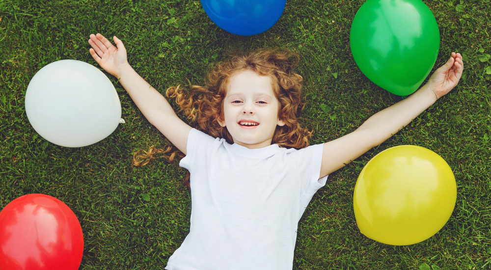 kid-smiling-with-balloons-around