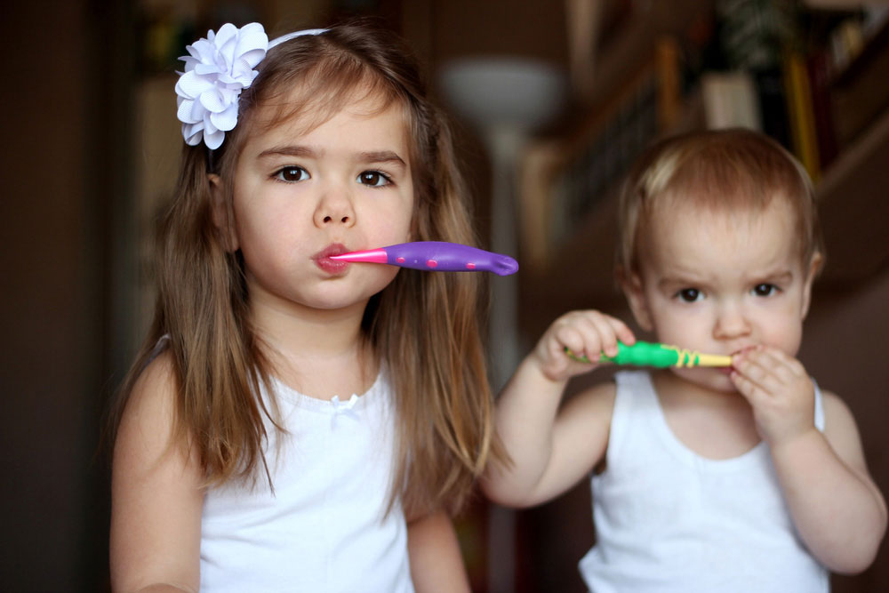 Two little girls brushing their teeth