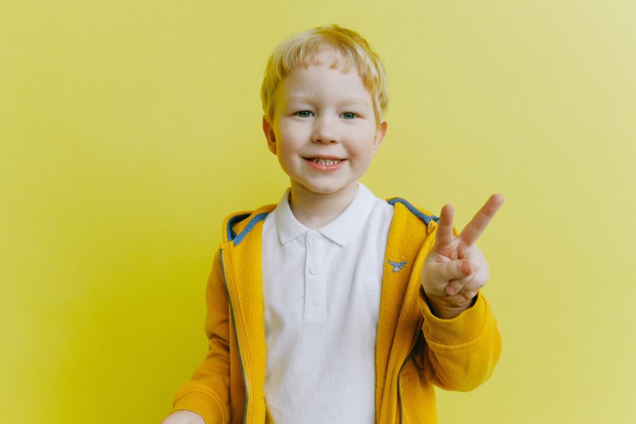 kid-smiling-with-peace-sign-at-pediatric-dentist
