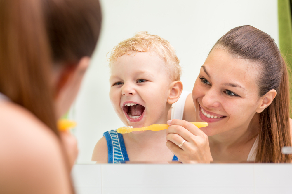 young-kid-learning-to-brush-teeth-with-his-mom