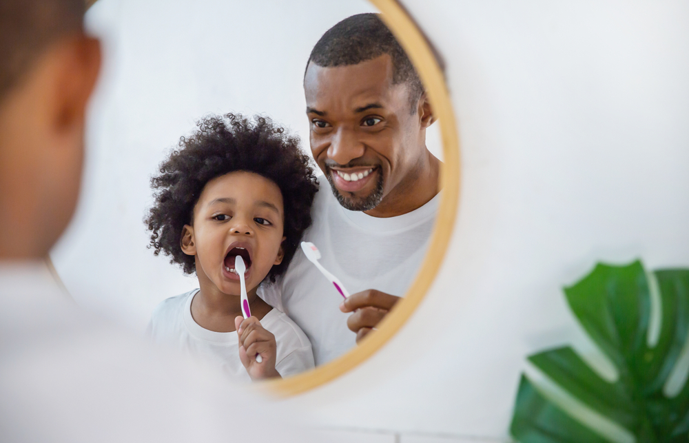 father and son brushing teeth together 