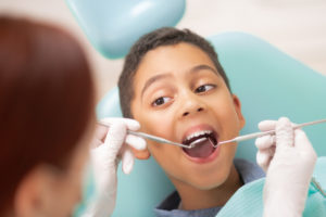 Boy Visiting Dentist. Handsome Dark-skinned Boy Opening Mouth While Visiting