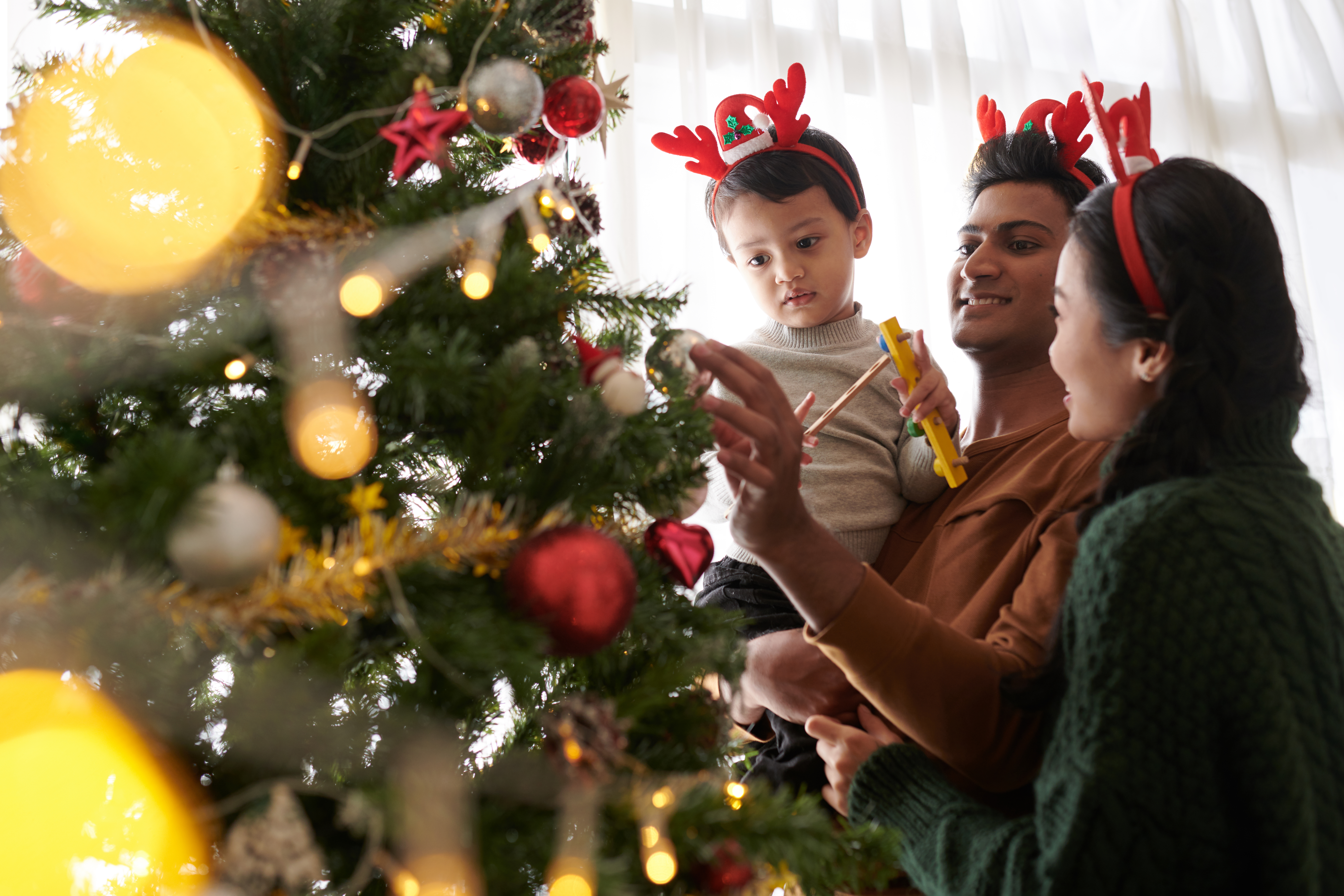 Child and parants with Christmas tree. 